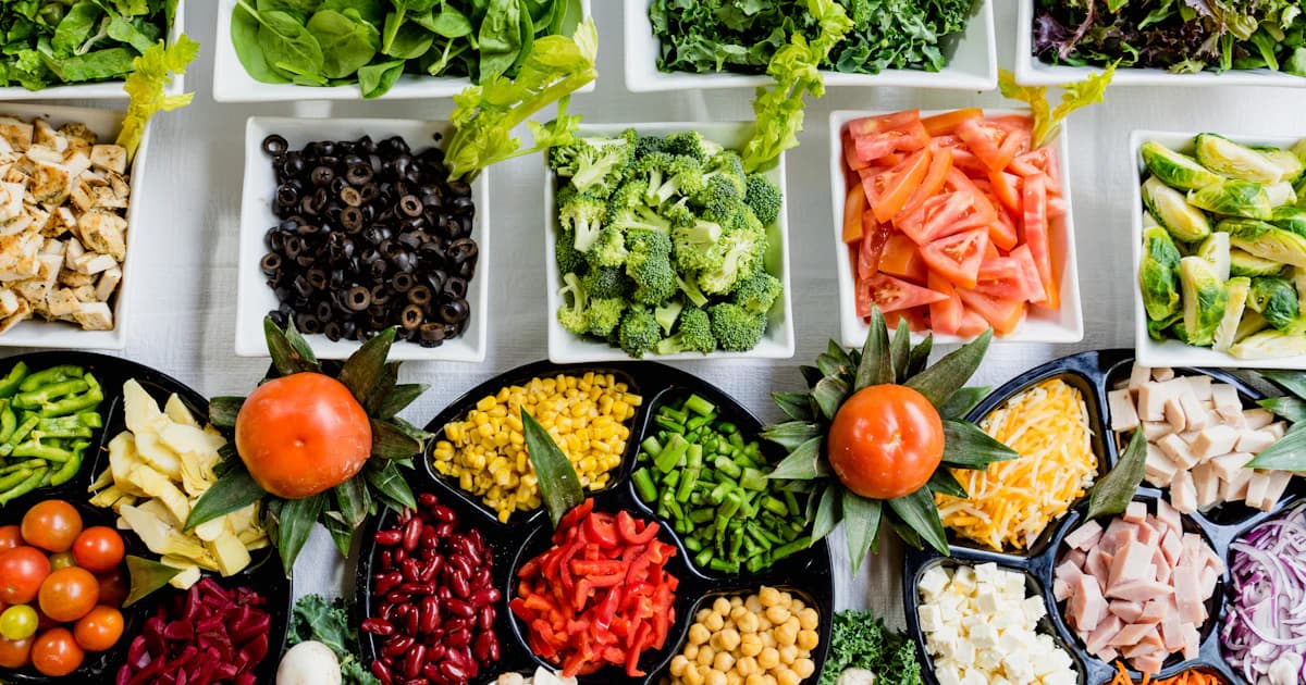 Bord vol kleurrijke groenten, fruit en volkoren producten als basis van gezonde voeding