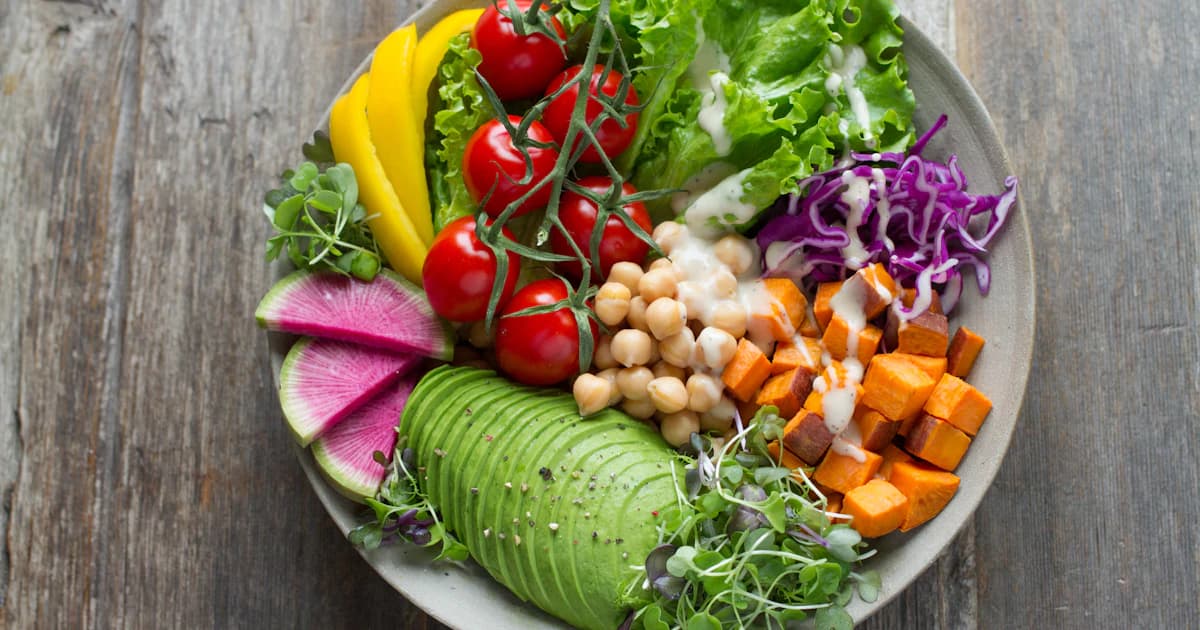 Bord met linzen, quinoa, geroosterde groente en avocado — plantaardige maaltijd